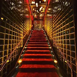 Gold-lattice staircase with red carpet at Catch LA