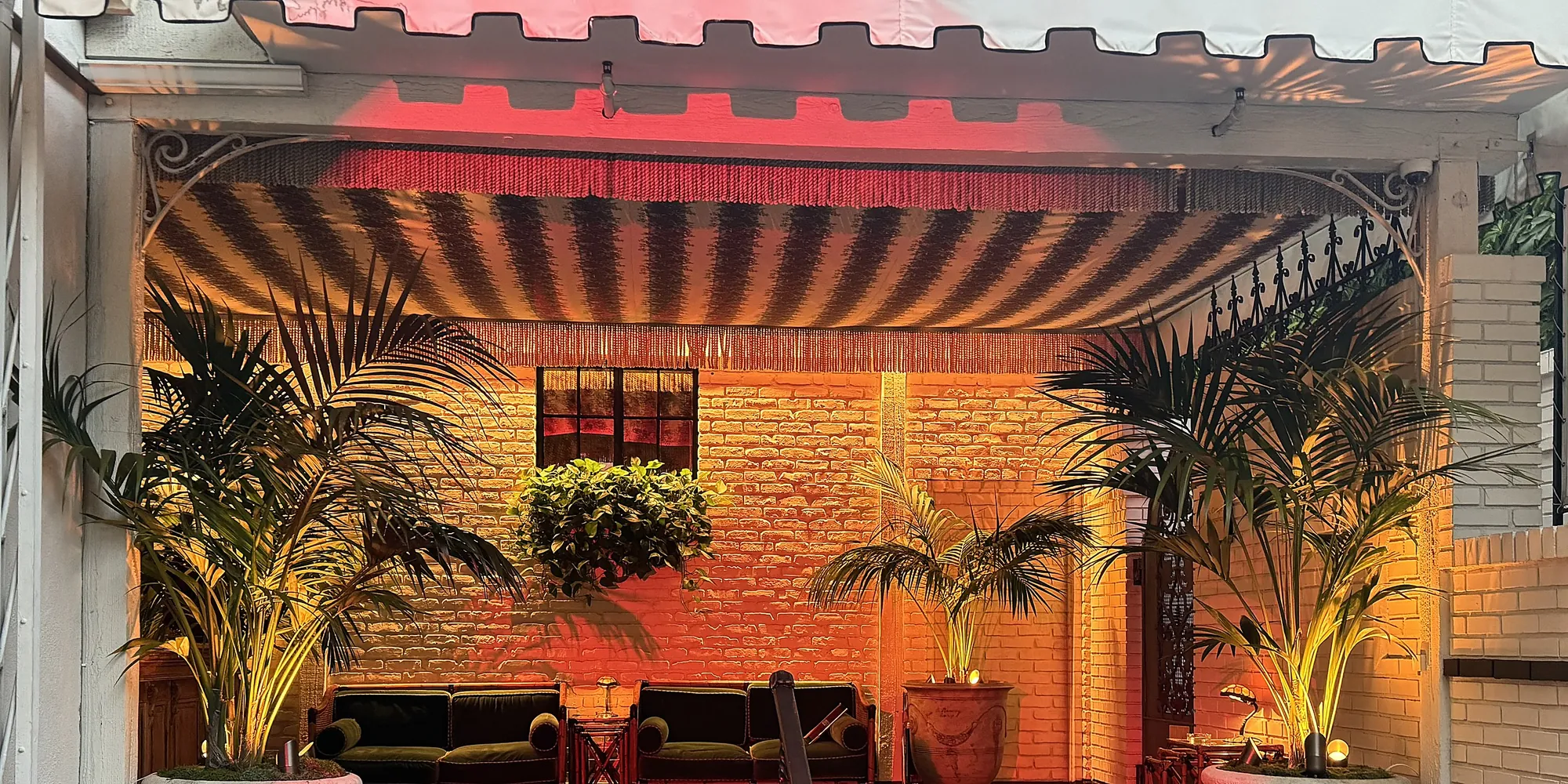Warm covered terrace with a striped awning and lounge seating at the Chateau Marmont