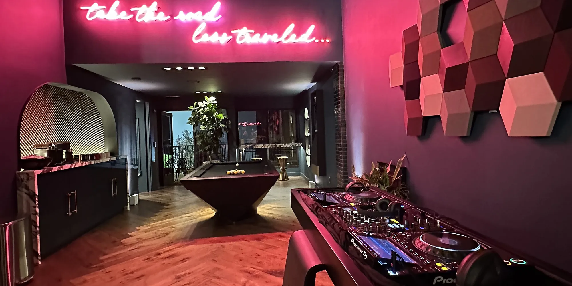 Red-lit lounge with the take-the-road-less-traveled neon and geometric wall panels at an Oppenheim Group event
