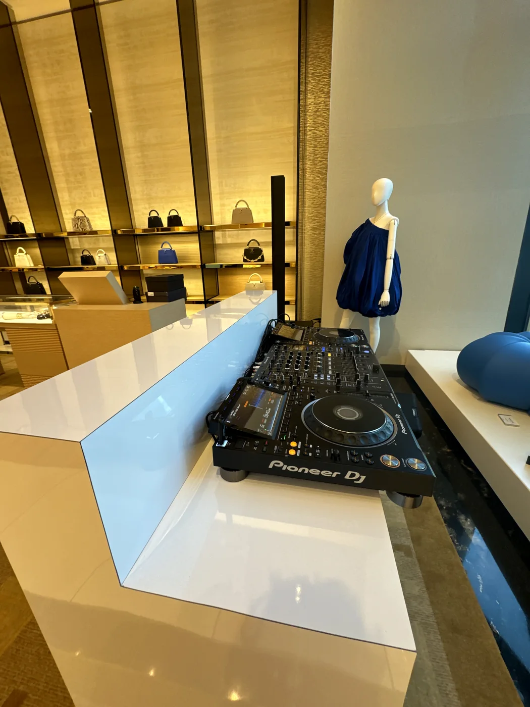 Pioneer DJ decks on the counter inside the Louis Vuitton store, with lit shelves behind