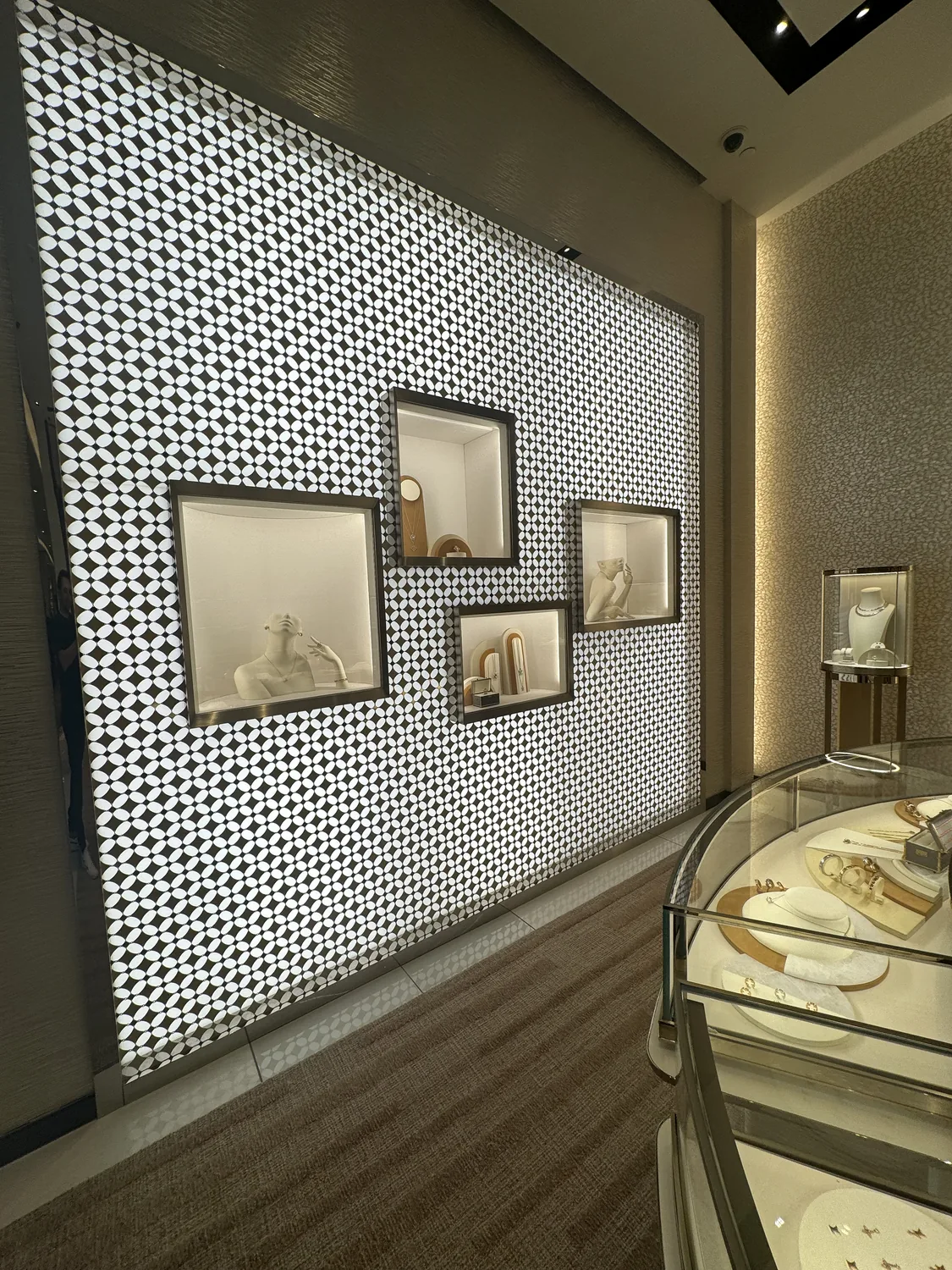 A backlit patterned wall with framed pieces and a display case inside the Louis Vuitton store